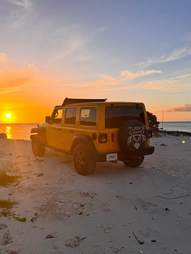 A yellow Wrangler by the water at sunset